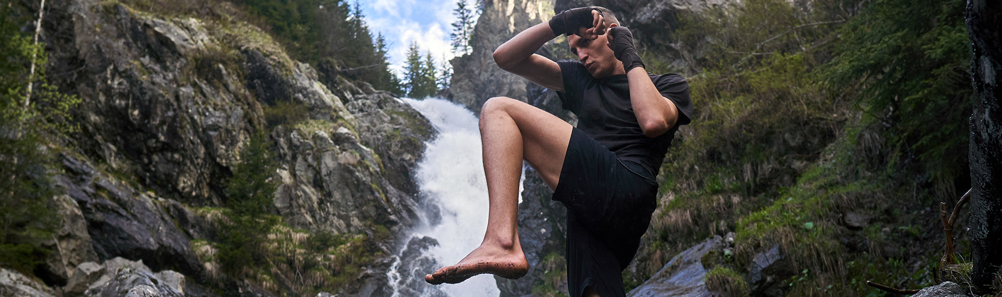 image d'un boxeur en pleine nature devant une cascade, représentant les sports de combats dans l'agenda sportif de CapRol