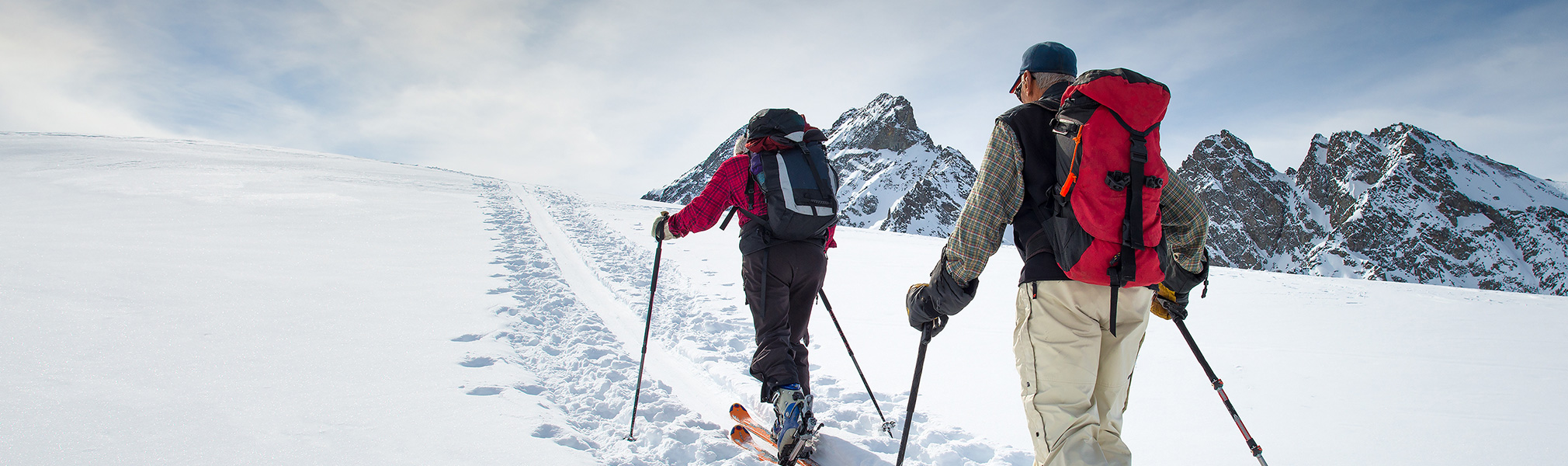 deux personnes agées faisant du ski de randonnée dans les montagnes et représentant les sports d'hiver dans l'agenda sportif de CapRol